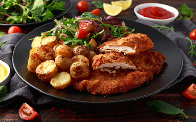 Homemade breaded pork schnitzel with roast potato and vegetables