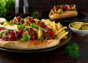 Meat balls hotdogs with french potato fries, chips, crinkle cut gherkins, ketchup and mustard. fast food