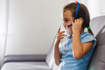 Little girl making inhalation with nebulizer at home. child asthma inhaler inhalation nebulizer...