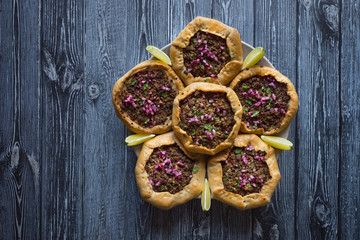 Open meat pies on dark wooden background. Top view
