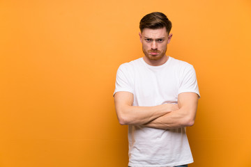 Redhead man over brown wall with sad and depressed expression