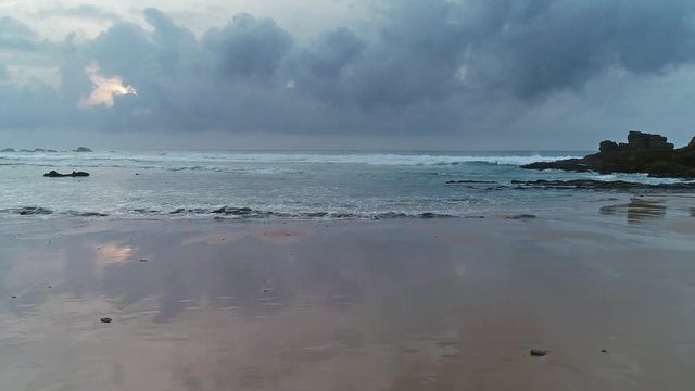 Flying over beautiful sandy beach with reflection clouds and sunset sky on Atlantic coast in Portugal, Europe, 4k