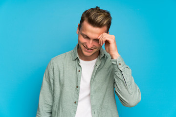 Blonde handsome man with green shirt laughing