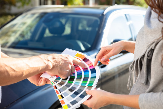 Man Showing Color Samples Standing In Front Of Car
