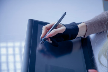 Hand of female graphic designer working with stilus and tablet