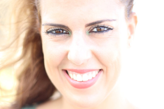 High key portrait of brunette young woman smiling on a sunny day.