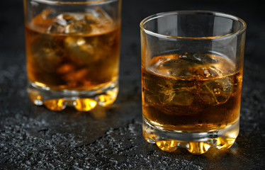 Glass of whiskey with ice on rustic background