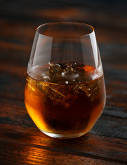 Glass of whiskey with ice on rustic table