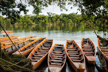 Fototapeta na wymiar Orange canoes docked near the shore of Canaimas’ Lagoon at the Amazon region of Venezuela