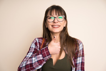 Young woman on ocher background giving a thumbs up gesture