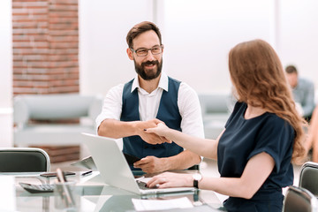 businessman and businesswoman shaking hands over the Desk