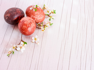 Easter eggs background. Eggs with eco decoration. Boiled in black wine and boiled in onion peels . On the white wooden table with gray lines and with flowers of wild plum.