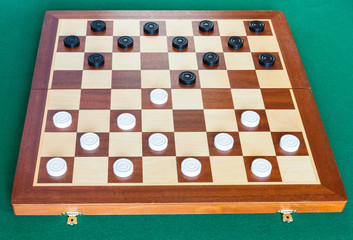 checkers on wooden board on green table