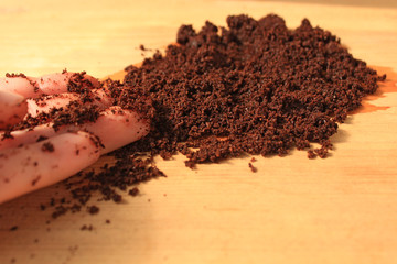 Coffee scrub for face and body, mask, cosmetics and care, wet ground coffee texture on wooden background.