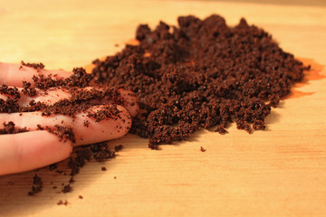 Coffee scrub for face and body, mask, cosmetics and care, wet ground coffee texture on wooden background.