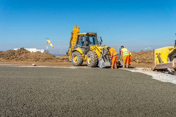 Construction site of road, building or airport with construction machinery (truck, bulldozer, excavator) and construction workers or engineers