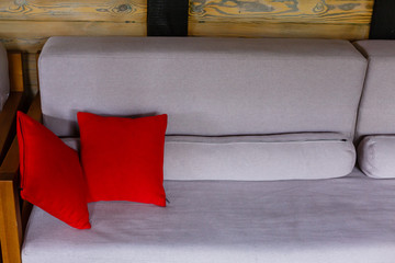 comfortable sofa with red pillows and red book on wooden table in living area at home