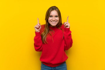 Young woman over yellow wall pointing up a great idea