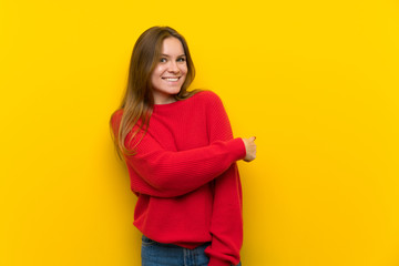 Obraz premium Young woman over yellow wall pointing back