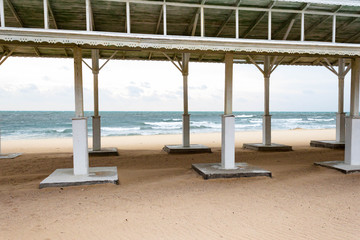Autumn sea cold stormy blue and green waves, white foam and clouds on sandy beach view through the empty bathing roof . Black Sea, Evpatoria, Crimea, Russia