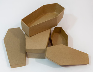 Cardboard coffins jumbled in a heap on white background.