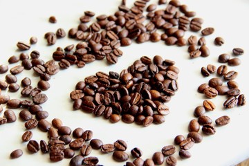 many scattered on the table roasted coffee beans in the shape of a heart, close up. coffee beans after roasting cool on the table, selective focus.