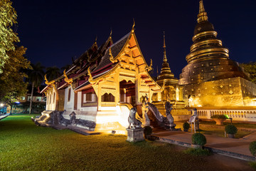 Fototapeta premium Chapel and golden pagoda at Wat Phra Singh Woramahawihan in Chiang Mai at twilight or night with stars in sky