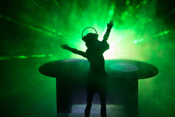 Dj club concept. Woman DJ mixing, and Scratching in a Night Club. Girl silhouette on dj's deck,...