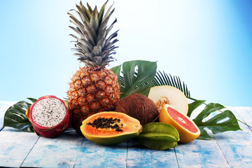 Fresh tropical Fruits on the beach with a palm leave. Assorted tropical fruits, orange,Ananas or pineapple and mango