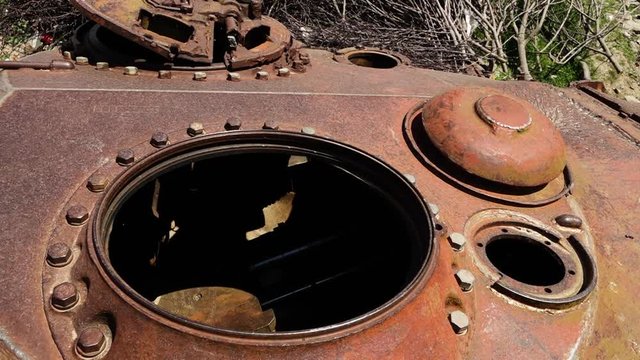 A hand held, extreme close up shot of the narrow rusty entrance to an abandoned tank.