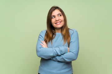 Young girl over green wall looking up while smiling