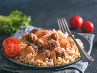 Bulgur dish idea and recipe. Bulgur with homemade roasted beef meatballs on dark blue background. Copy space for text. Shallow DOF