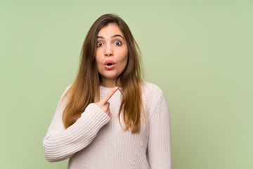 Obraz premium Young girl with white sweater pointing finger to the side and presenting a product