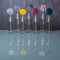 Bright and colorful lollipopы in clear bottles standing on the glass table. Concept of fresh drinks. Concept of holidays.