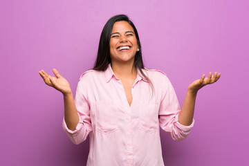 Young Colombian girl over purple wall smiling a lot