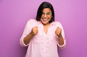 Young Colombian girl over purple wall celebrating a victory