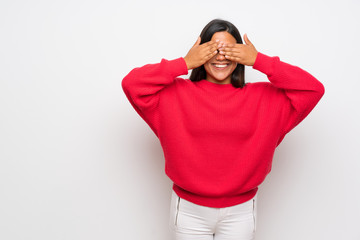 Young Colombian girl with red sweater covering eyes by hands