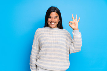 Young Colombian girl with sweater showing an ok sign with fingers