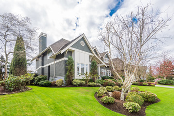 Beautiful exterior of newly built luxury home. Yard with green grass and walkway lead to front...