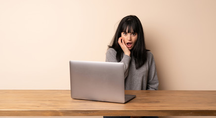 Young woman working with her laptop surprised and shocked while looking right