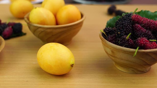 Cupcake in a wooden plate with ripe tropical fruit in wooden bowl on a wooden board