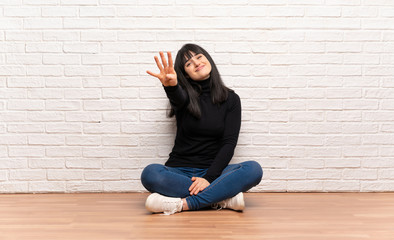 Woman sitting on the floor happy and counting four with fingers