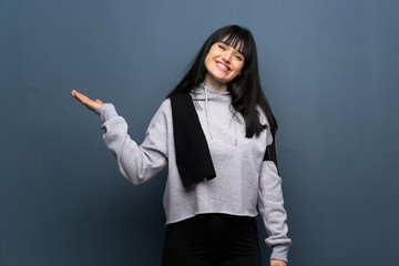 Young sport woman holding copyspace imaginary on the palm to insert an ad