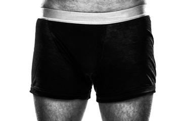 Closeup of a masculine hairy man standing in black boxer shorts isolated on white background - Concept of impotent boyfriend, husband or lover, sexual gdesire and sex confidence in the bedroom