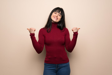 Young woman with red turtleneck giving a thumbs up gesture with both hands and smiling