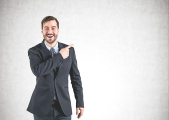 Smiling businessman pointing sideways, mock up