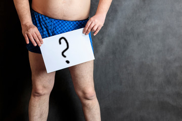Man in shorts on the background of the school board, a question mark, a blank sheet of paper.