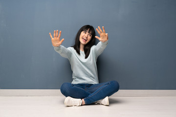 Woman sitting on the floor counting nine with fingers