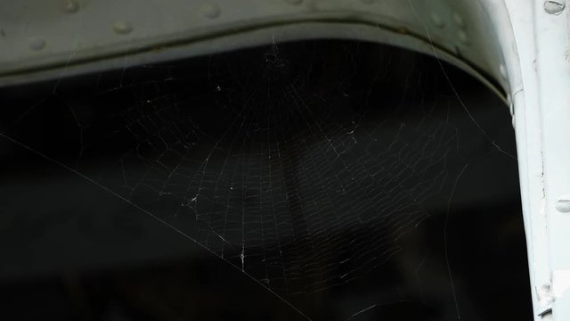 A steady, extreme close up shot of a spider web in the corner of an entrance. 
