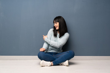 Woman sitting on the floor pointing back